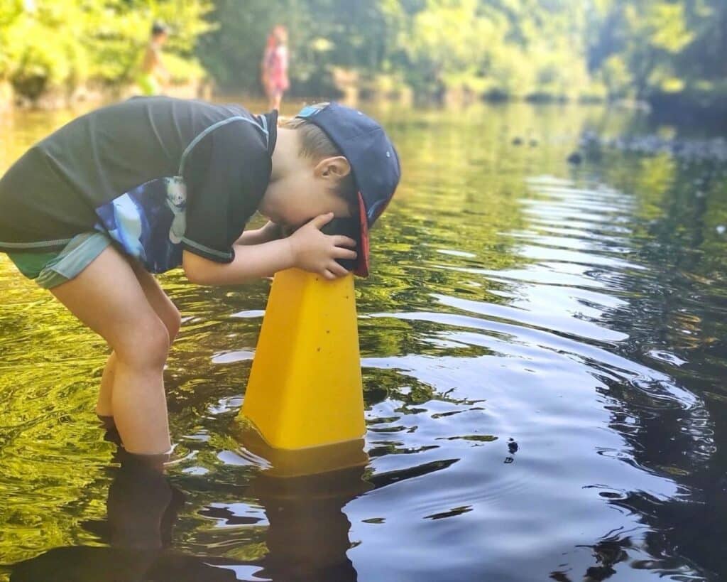 A child looks into the river with a underwater viewer- these river workshops help children get hands on